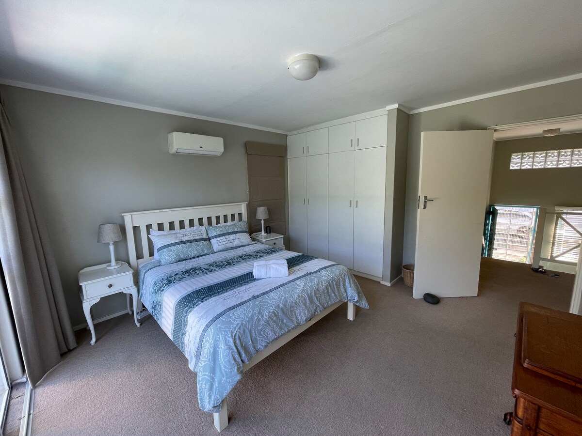 楼上的第二间卧室配有标准双人床、橱柜和通往阳台的滑动门。 