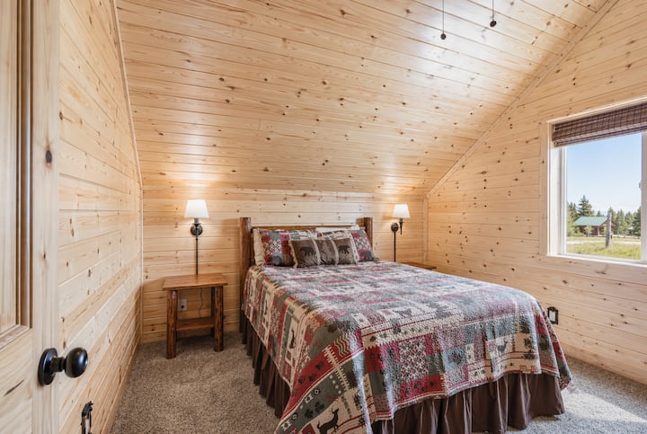 Charming upstairs bedroom with a queen bed, warm wood accents, and soft natural light—creating a peaceful and cozy retreat.