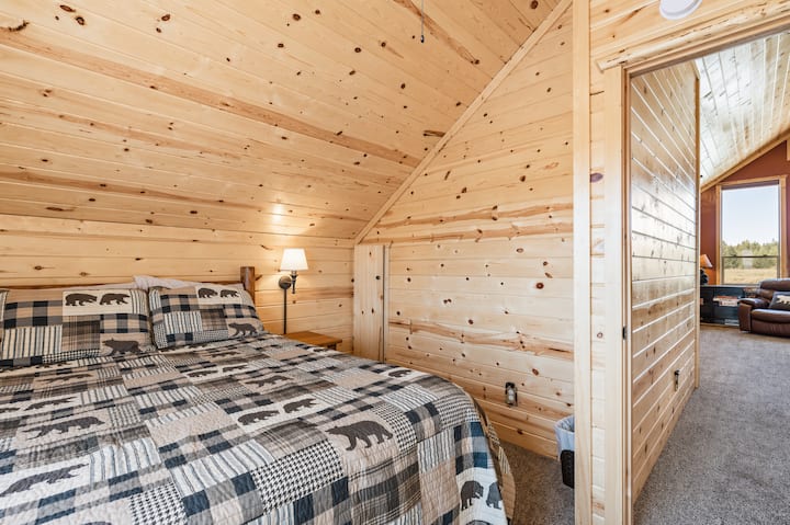 Upstairs bedroom with a cozy queen bed, vaulted wood ceilings, and warm natural finishes—perfect for a quiet and relaxing stay.