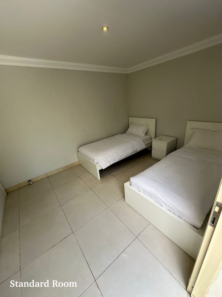 a small room with 2 single beds without attached bathroom., extra bathroom is located right outside near the kitchen area. 