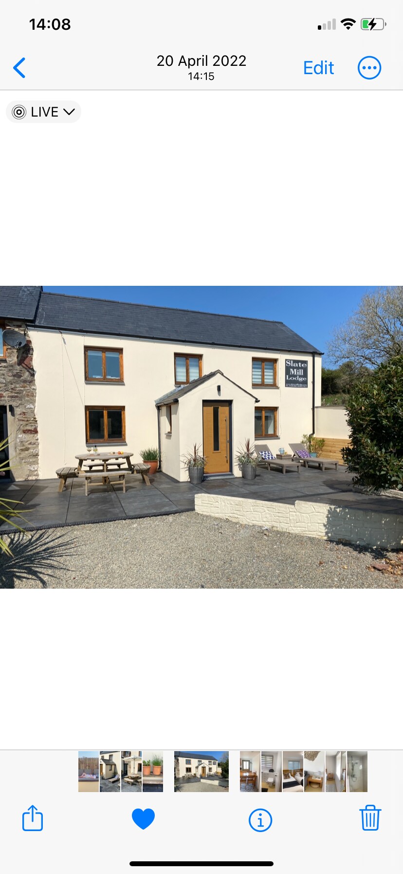 The exterior of Musselwick is shown with a modern farmhouse style. A welcoming entrance is positioned at the center, flanked by planters. A patio area features multiple picnic tables for outdoor seating, surrounded by gravel pathways and landscaped borders.