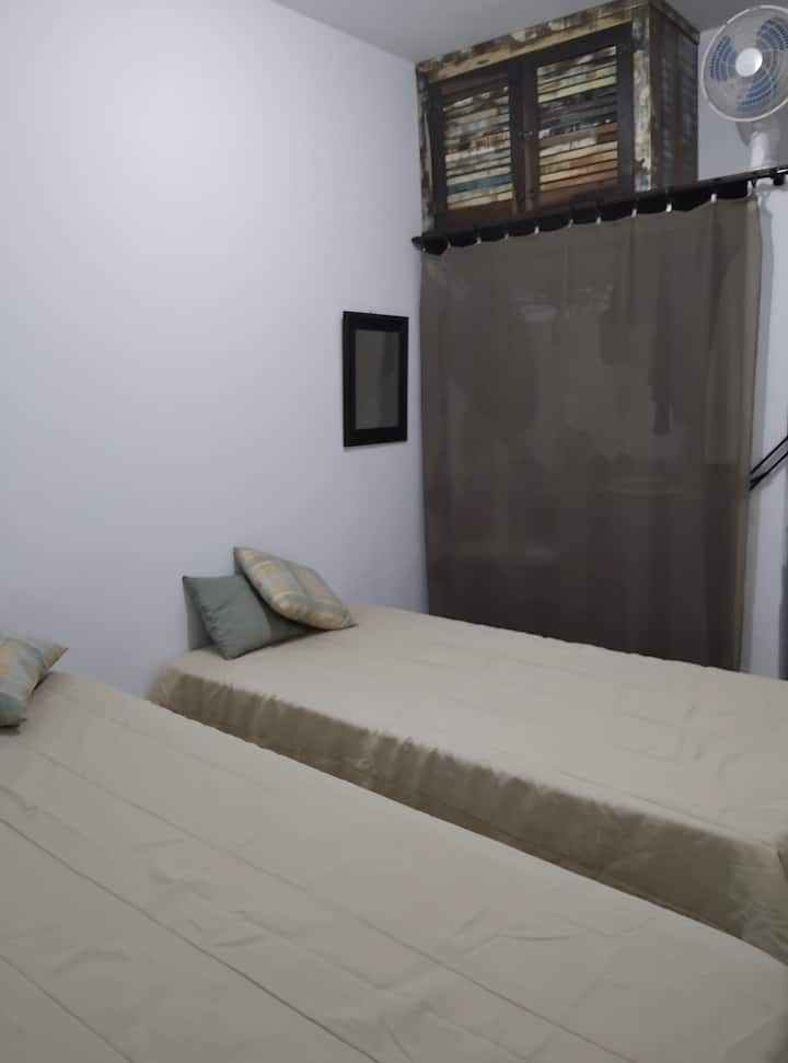 2 lits simples et un placard avec un rideau. Ventilateur disponible.