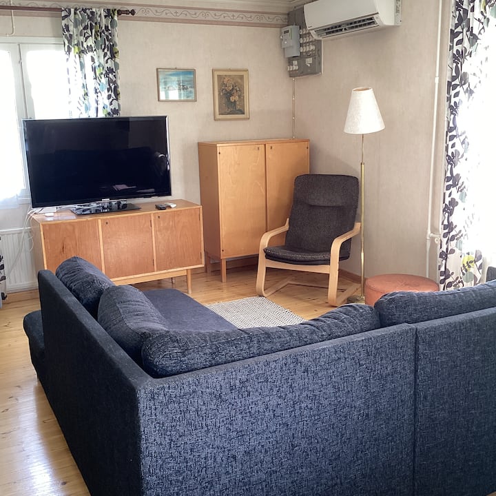 In the living room, or "pirtti," there is a sofa that can be converted into a single bed if needed. The room also has a TV with free channels and an air-source heat pump for cooling if needed.