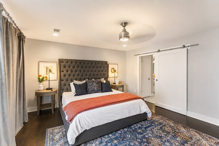 Wake up in the master suite — king bed with a charcoal tufted headboard, barn door, and private balcony doors to greet the morning.