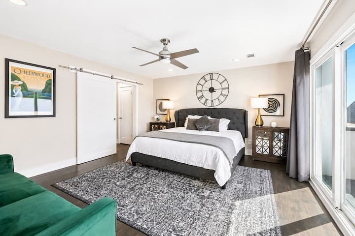 King size bed with a tufted headboard and bold decor pieces create a stylish retreat - Sliding barn door offers access to a private ensuite, adding rustic modern flair - Neutral tones are balanced by warm lighting and classic mirrored nightstands