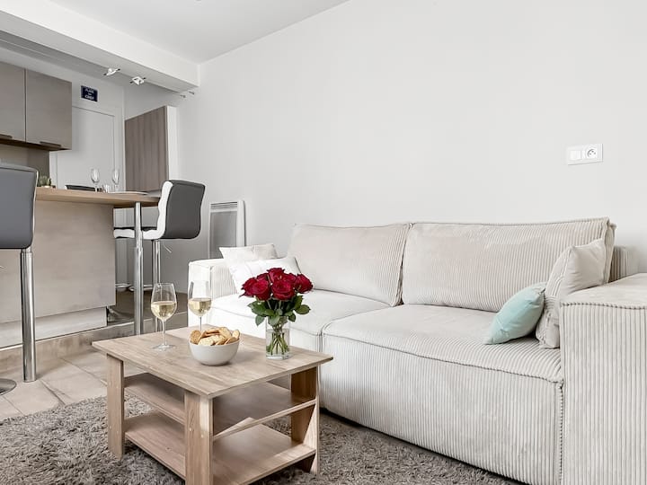 Rummelig stue med fløjlssofa og aircondition. Det åbne layout, der fører hen til køkkenet, skaber en venlig og moderne atmosfære under dit ophold.