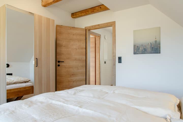 Hofseitiges Schlafzimmer im 1. Stock mit 1.80 m breitem Doppelbett und Stockbett. | Courtyard-facing bedroom on the 1st floor with 1.80 m wide double bed and bunk bed.