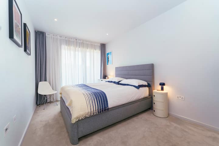 宽敞宁静的卧室，可通往阳台，配有加大双人床、遮光百叶窗、抽屉柜和衣柜挂衣空间。