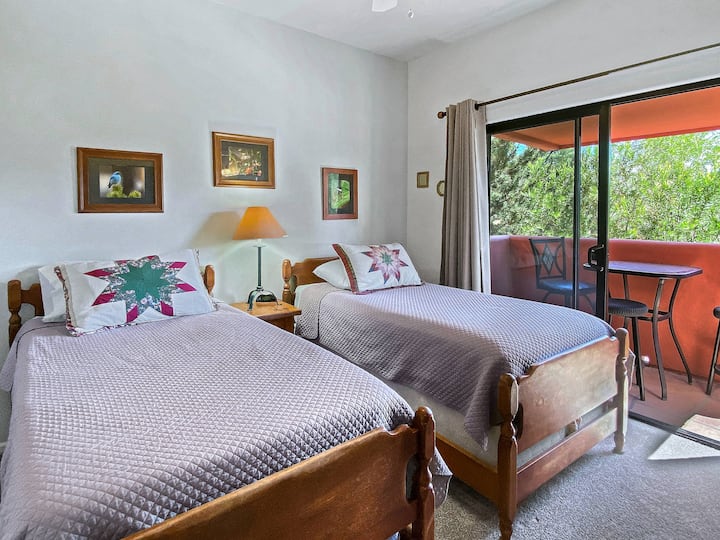 Back bedroom featuring two twin beds that can be pushed together to create a king bed, a dresser for storage, an HDTV, and sliding doors that open to a private balcony.