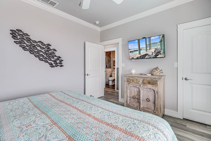 Your coastal-themed bedroom features a comfortable bed, charming wall art, and a flat-screen TV for relaxing evenings after beach adventures.