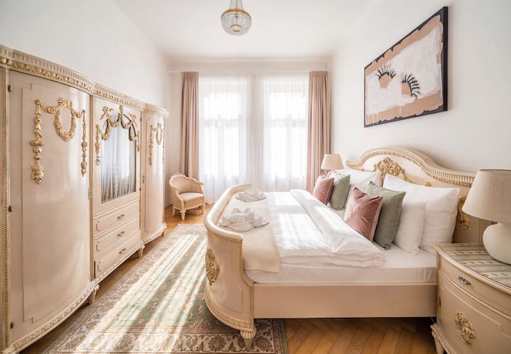 Chambre de style royal avec un cadre de lit sculpté, une armoire assortie et une lumière naturelle douce.