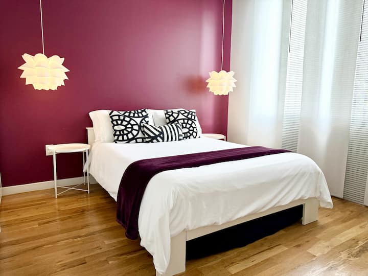 Cama queen súper cómoda en el dormitorio púrpura con vistas al parque infantil. ¡Nos preocupamos mucho por la calidad del sueño y estamos orgullosos de que los huéspedes hayan comentado que nuestra casa tiene “las camas más increíbles”!