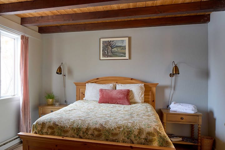 Nueva cama tamaño queen con sábanas de estilo campestre, mesas auxiliares de roble, luces personalizadas. Esta habitación está junto al comedor y la sala de estar y frente al baño accesible.