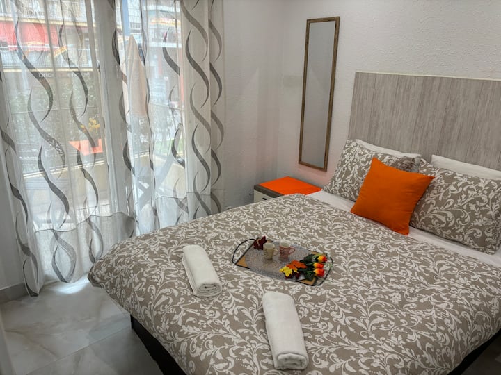 Acogedor dormitorio con balcón con vistas a la calle. Tiene una cama doble y una pared divertida.