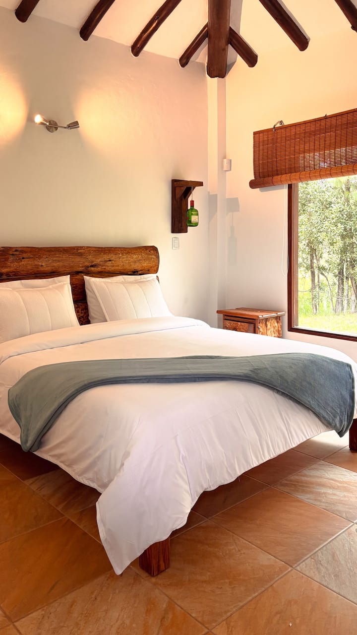Chambre spacieuse équipée d'un linge de maison impeccable, de tables de chevet artisanales et d'une ambiance calme.