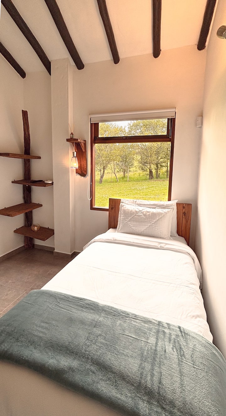 Chambre confortable avec étagère en bois naturel et vue directe sur les prairies de la propriété
