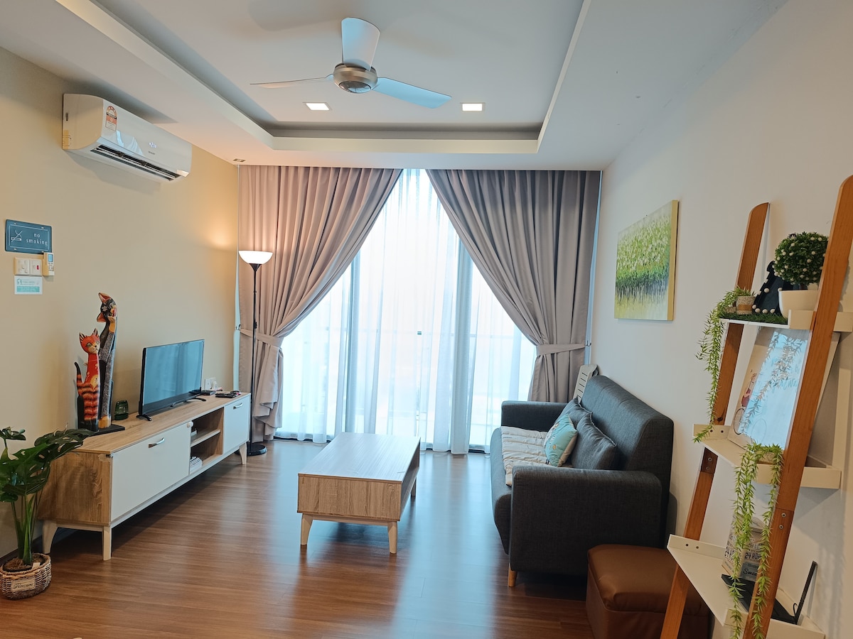 The living room features a comfortable sofa paired with a coffee table and a TV console. A television is mounted on the wall, and natural light streams through large curtains. A ceiling fan and indoor plant add to the inviting atmosphere.