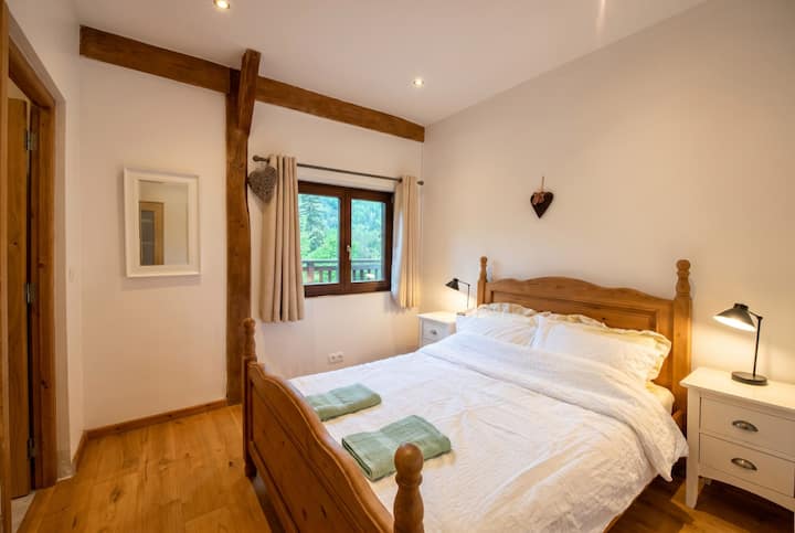 Une chambre paisible avec une vue depuis le balcon et des poutres en bois rustiques.