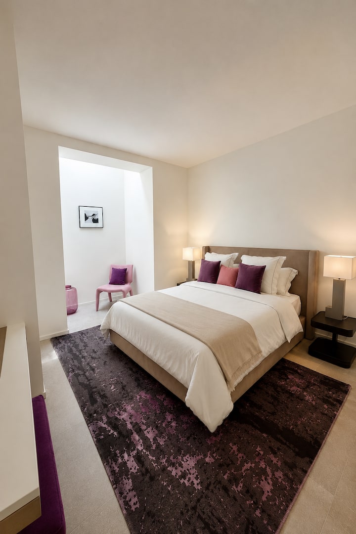 Lower-level bedroom  featuring a 160 cm Roche Bobois bed, skylight ceiling bringing in natural light, and a private en-suite bathroom with bathtub and toilet. Includes a TV and Daikin air conditioning for comfort and a relaxing stay.