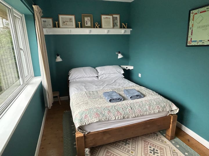 Butterick. A comfortable double bed, wardrobe and shelf storage. A large window overlooks the front garden and fields beyond 