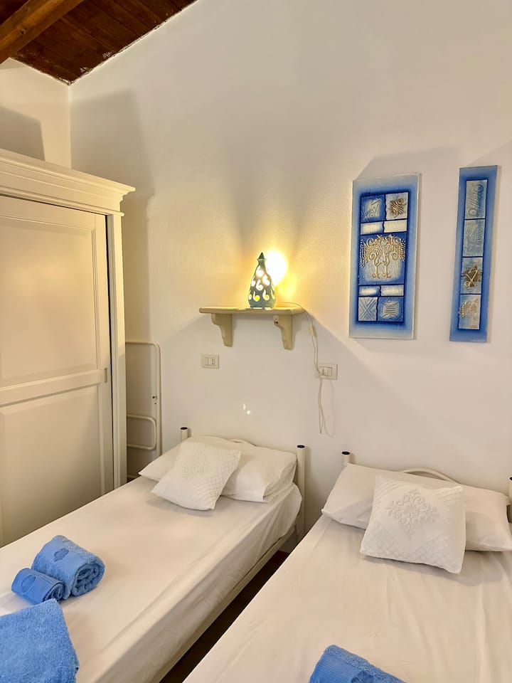 Un dormitorio luminoso y funcional, con dos camas individuales y un cómodo armario con puertas correderas. Perfecto para niños, amigos o huéspedes, ofrece un espacio acogedor y bien organizado, en línea con el estilo marino del apartamento.