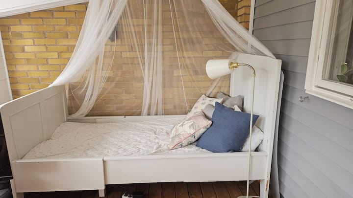 Bed met klamboe in glazen patio. 