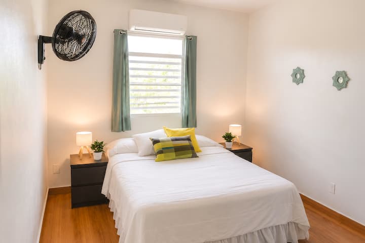 Cozy second bedroom with queen bed, AC, soft lighting, and a calm atmosphere for restful nights after exploring Puerto Rico.