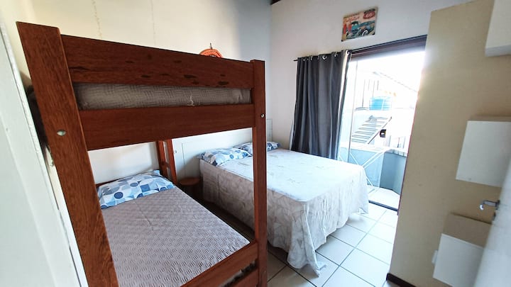 Quarto de casal e beliche, com ar condicionado e acesso à uma pequena varanda nos fundos.