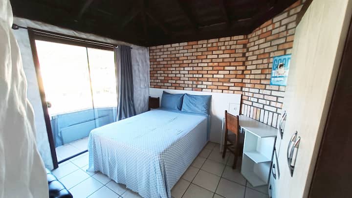 Quarto de casal com uma pequena varanda nos fundos.