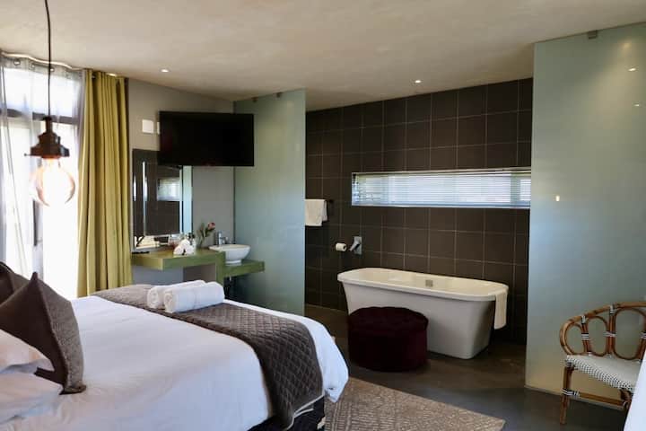 Dormitorio con baño privado, bañera y ducha con vista al mar