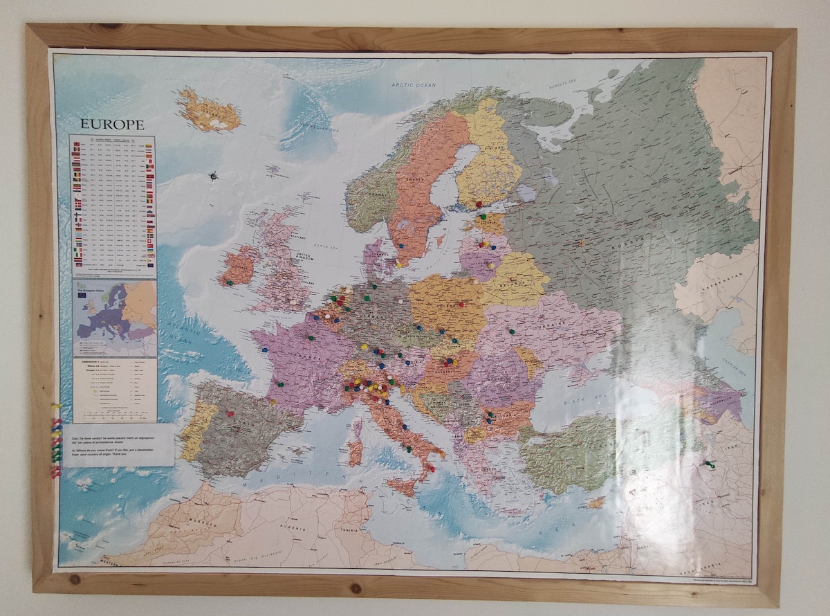 A detailed map of Europe is presented, framed and mounted on the wall. Various colors denote different countries and regions, while numerous pins indicate points of interest. A legend in the top left corner explains the symbols and colors used on the map.
