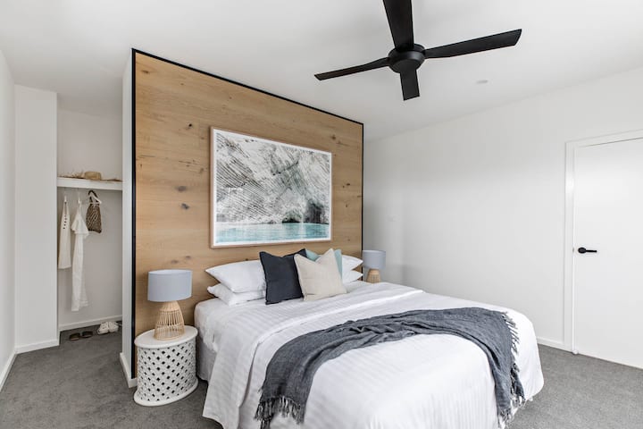 Elegante dormitorio tamaño king con pared de madera y ventilador de techo