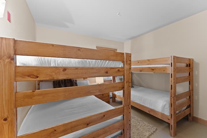 تحتوي غرفة نوم الضيف على سريرين بطابقين في برنامج Ivory White Bedding وتلفزيون بشاشة مسطحة.