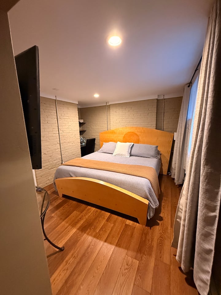 king size bed in basement bedroom that is found off of basement TV room. This is a above ground level walk out area has large windows