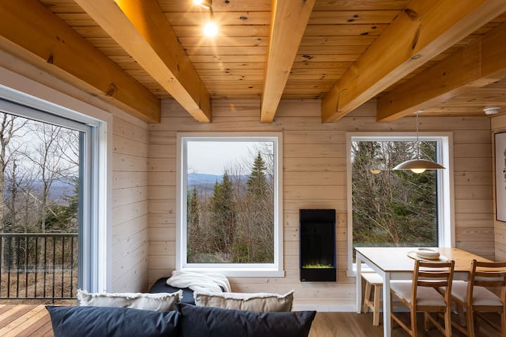 Living room area with electric fireplace, dining area and kitchenette with views of the mountains and the beautiful sunsets.