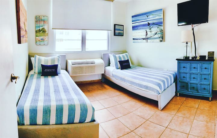 The second bedroom has new comfortable beds, a closet, a clothes chest, air conditioning, a ceiling fan, a Bluetooth speaker, and a smart TV with cable and Roku.