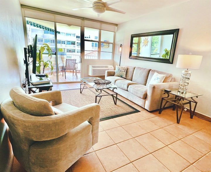 The spacious condo offers modern furnishings, air conditioning throughout, smart TVs, fast Internet, Bluetooth speakers, and an open balcony with views of the garden and pool. 
