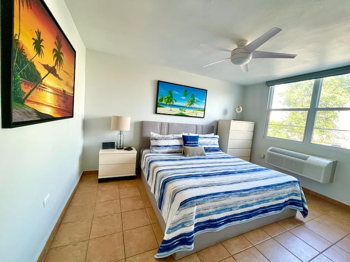 The spacious master bedroom suite has a new Bassett king bed, a walk-in closet, a clothes chest, air conditioning, a Bluetooth speaker, a ceiling fan, and a SmartTV with Roku. The full-size bathroom is part of the suite.