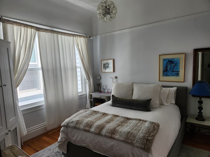 La cama y la habitación queen recientemente movidas se ven más grandes.  Es mejor para parejas.  Cada uno tiene una mesita de noche y luz.  Al otro lado de la cama hay un televisor y una puerta al baño privado.