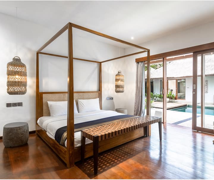 Master Bedroom (Bedroom number 4) – Spacious room with a king-size bed, premium King Koil mattress, and 300-thread-count linens. Features wooden floors, soft lighting, handcrafted decor, and direct pool access for ultimate comfort.