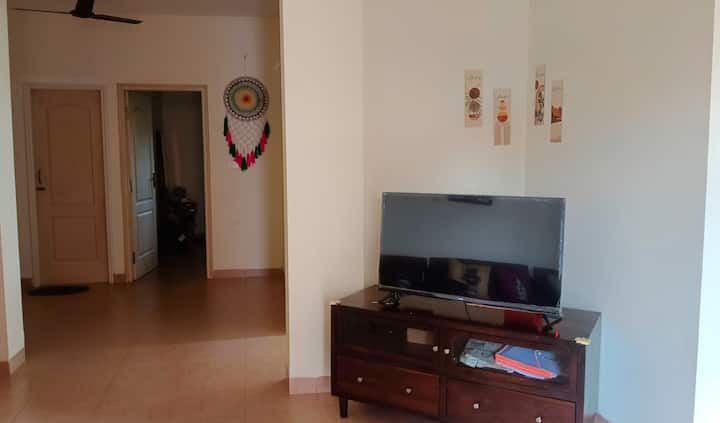 A sleek TV unit bathed in natural light, with a dream catcher view casting delicate shadows, creates a serene blend of modernity and mysticism.