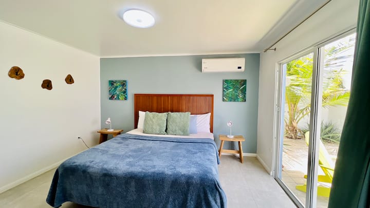 A comfortable bedroom with king size bed, air conditioning and a view to the patio. 