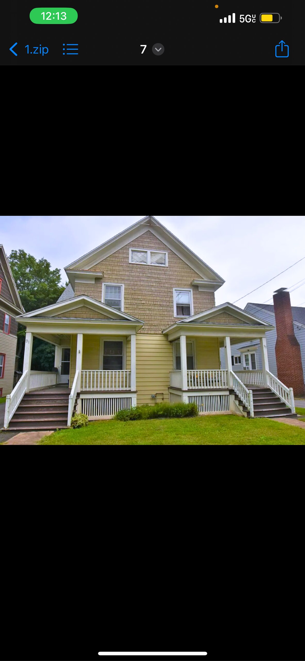 The exterior of a charming two-story home is depicted, featuring a light yellow facade complemented by a shingle-style upper section. Two covered porches with white railings provide welcoming entryways, while a lush green lawn enhances the inviting appearance of the property.