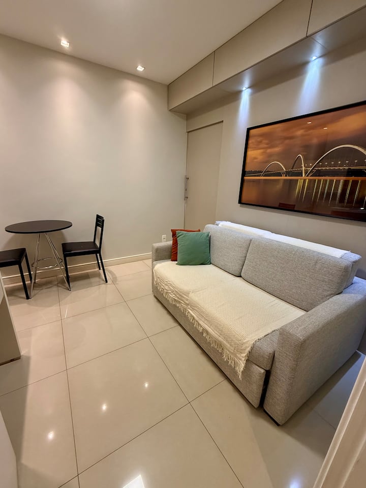 Sebule ndogo na yenye starehe yenye sofa na meza ya bistro inayofaa kwa milo ya haraka au kazi.