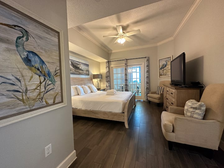 Hlavná spálňa 1 s manželskou posteľou King, dvoma nočnými stolíkmi, komodou, veľkým televízorom a stoličkami. 