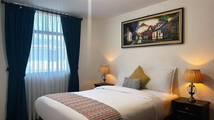 Lichte en elegante kamer met een tweepersoonsbed, decoratie geïnspireerd door La Antigua Guatemala en een schilderij van de vulkaan als hoofdrolspeler. Het beschikt over een kast en verduisterende gordijnen voor een goede nachtrust.