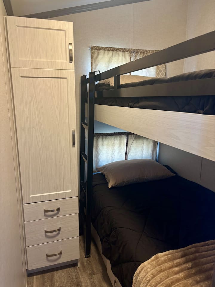 Dvojlôžko nad jednolôžkovými palandami. USB zásuvka vedľa poschodových postelí. Dostatok úložného priestoru v zásuvkách pod posteľou a skriňa s ďalšími policami a zásuvkami. 