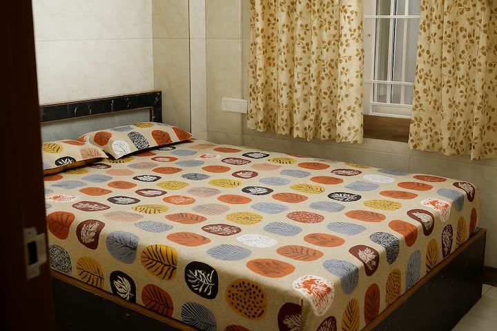 Cómodo dormitorio con una cama acogedora, sábanas limpias y un ambiente tranquilo, ideal para una estancia relajante en esta casa de familia en Coimbatore.