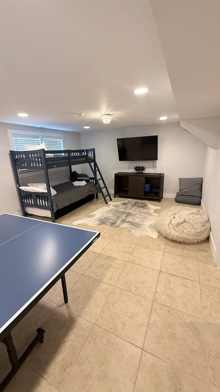 Recámara con dos camas individuales, una Smart TV, mesa de ping-pong y cómodos asientos en una casa vacacional de 5 recámaras en Mount Pleasant, Carolina del Sur.