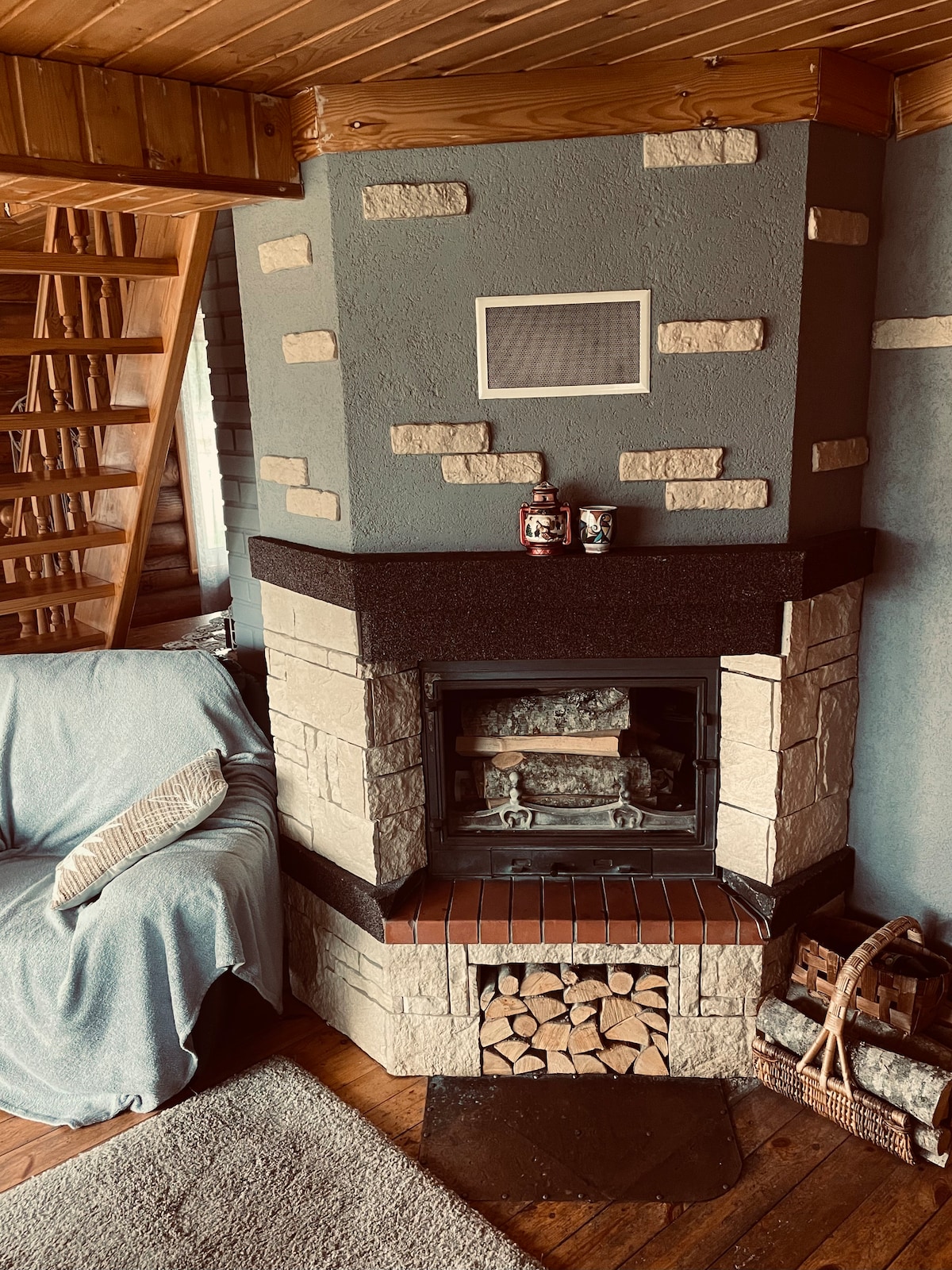 Obývacia izba na prízemí je spojená s kuchyňou, má krb a rozkladaciu pohovku.